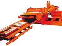 Industrial metal shredder machine with an orange body and conveyor belt, isolated on a white background.