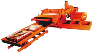 Industrial metal shredder machine with an orange body and conveyor belt, isolated on a white background.